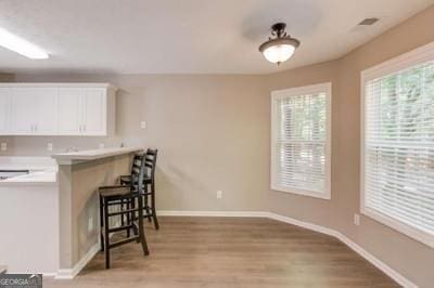 kitchen featuring light wood-type flooring, baseboards, white cabinets, and a breakfast bar area