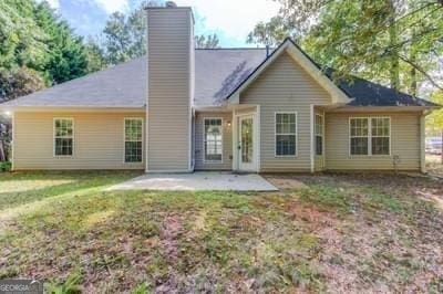 back of property with a patio, a yard, and a chimney