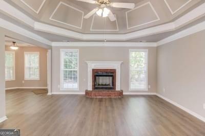 unfurnished living room with a brick fireplace, ornamental molding, coffered ceiling, and wood finished floors