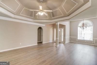 empty room featuring arched walkways, coffered ceiling, crown molding, and wood finished floors