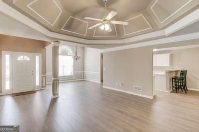 interior space with a ceiling fan, coffered ceiling, ornate columns, and wood finished floors