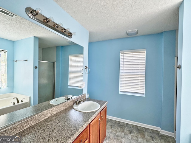 full bath with a textured ceiling, vanity, visible vents, baseboards, and a stall shower