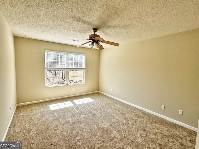 carpeted spare room with a ceiling fan, visible vents, a textured ceiling, and baseboards