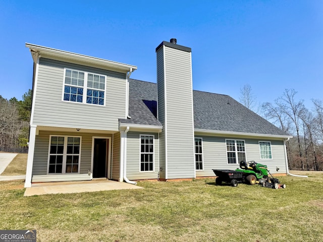 rear view of property featuring a patio area, a shingled roof, a chimney, and a yard