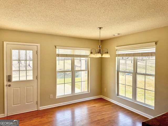 interior space with hardwood / wood-style flooring, baseboards, a chandelier, and a textured ceiling