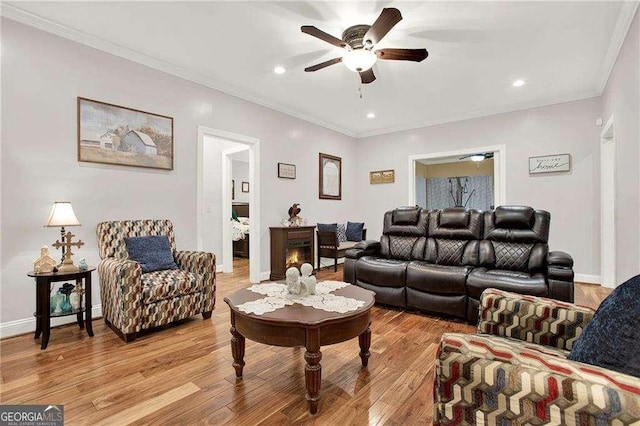 living area with light wood-type flooring, baseboards, ornamental molding, and ceiling fan