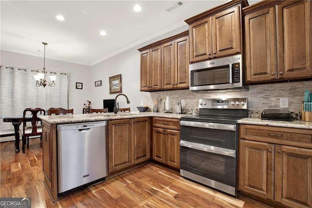 kitchen with crown molding, visible vents, appliances with stainless steel finishes, a sink, and a peninsula