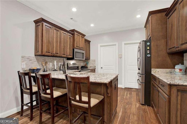 kitchen with stainless steel appliances, a peninsula, dark wood-style flooring, ornamental molding, and decorative backsplash