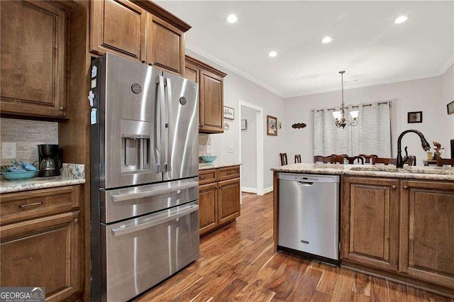 kitchen featuring stainless steel appliances, ornamental molding, a sink, and dark wood finished floors