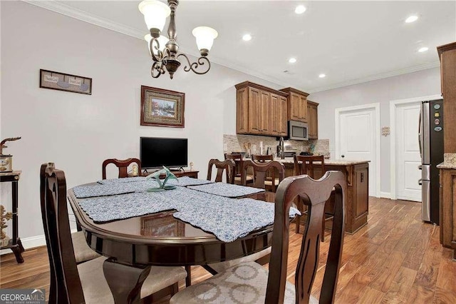 dining area with an inviting chandelier, baseboards, ornamental molding, and wood finished floors