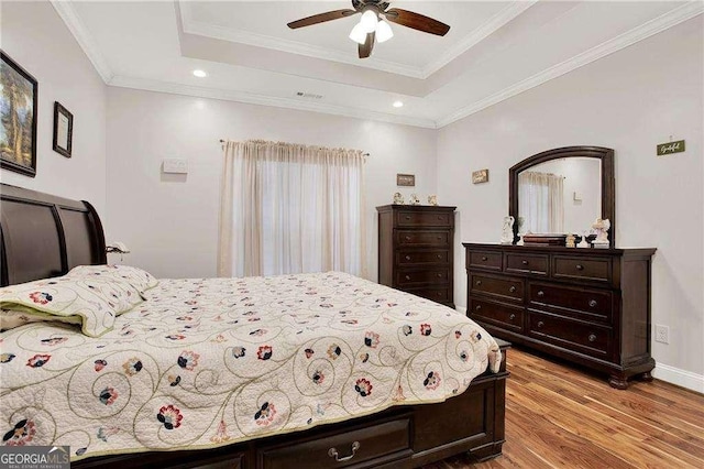 bedroom featuring crown molding, a raised ceiling, visible vents, and light wood-style floors