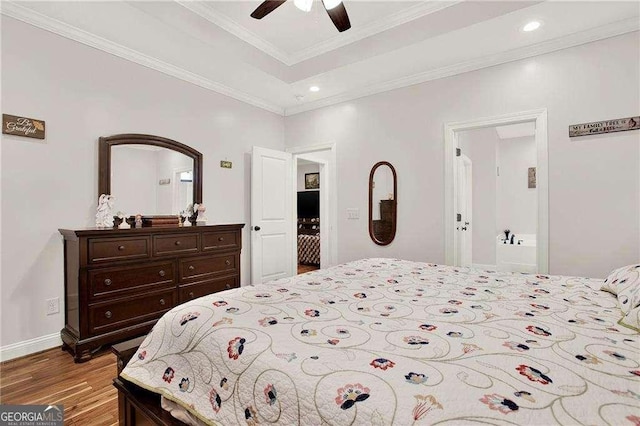 bedroom featuring recessed lighting, wood finished floors, baseboards, a raised ceiling, and crown molding