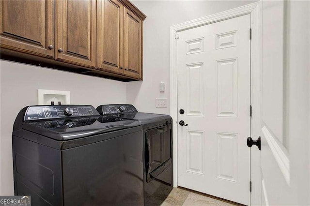 clothes washing area with separate washer and dryer and cabinet space