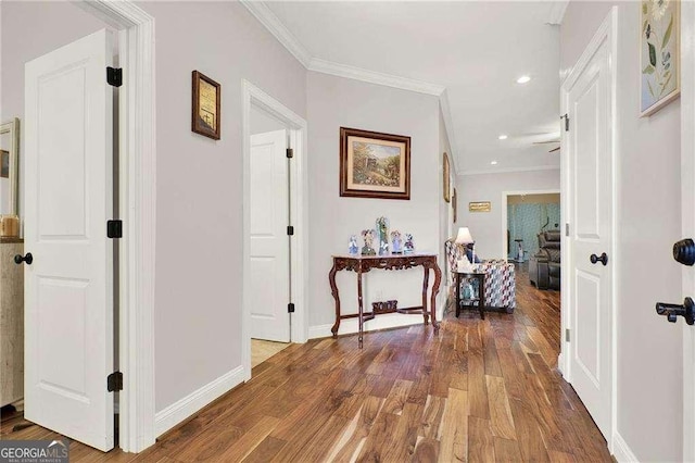 corridor featuring baseboards, ornamental molding, wood finished floors, and recessed lighting