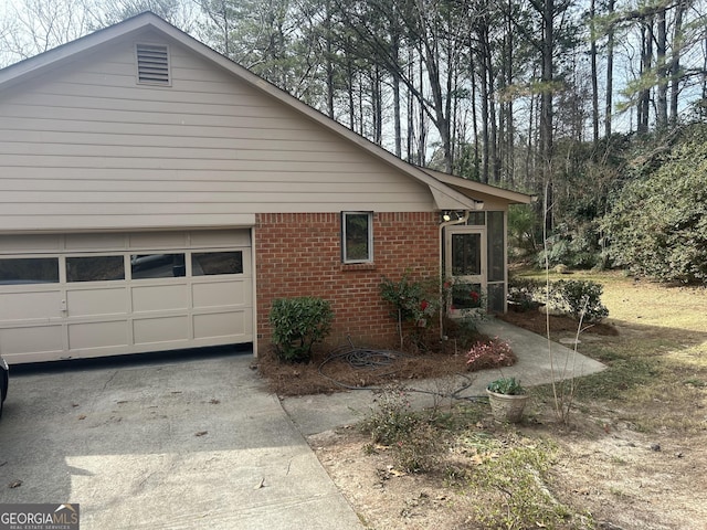 view of home's exterior with brick siding, concrete driveway, and a garage