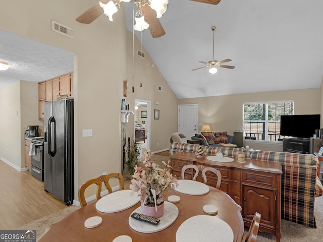 dining area featuring high vaulted ceiling, light wood-type flooring, visible vents, and baseboards