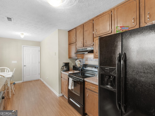 kitchen featuring black appliances, brown cabinets, visible vents, and under cabinet range hood