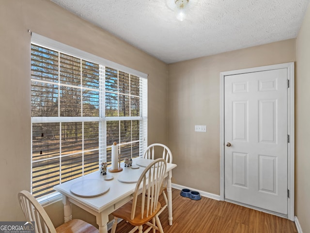 dining space with a textured ceiling, wood finished floors, and baseboards