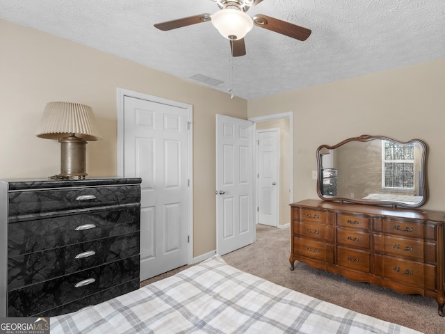 carpeted bedroom featuring a textured ceiling, a ceiling fan, visible vents, and baseboards