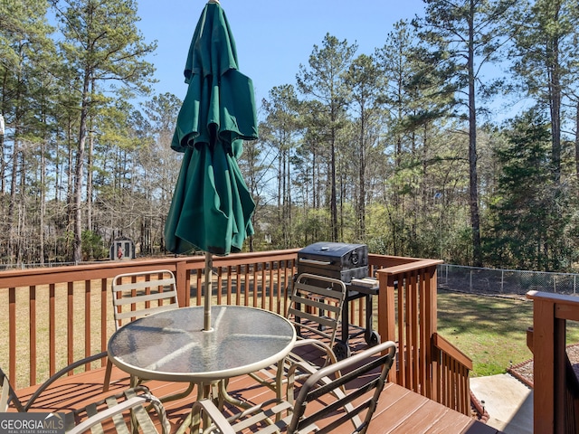 wooden terrace featuring outdoor dining area, a yard, and fence