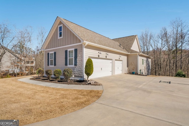 view of property exterior featuring driveway, a garage, a lawn, roof with shingles, and board and batten siding