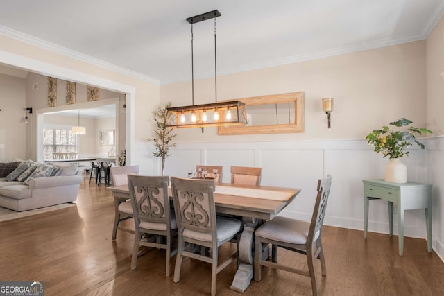 dining area featuring crown molding, wood finished floors, and wainscoting