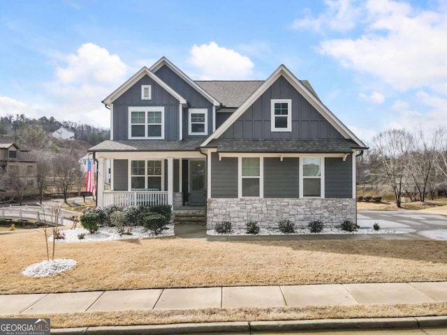 craftsman-style house featuring covered porch, stone siding, a shingled roof, and board and batten siding