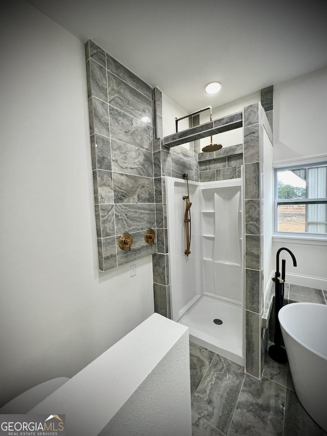 full bathroom featuring a freestanding bath, marble finish floor, and a walk in shower