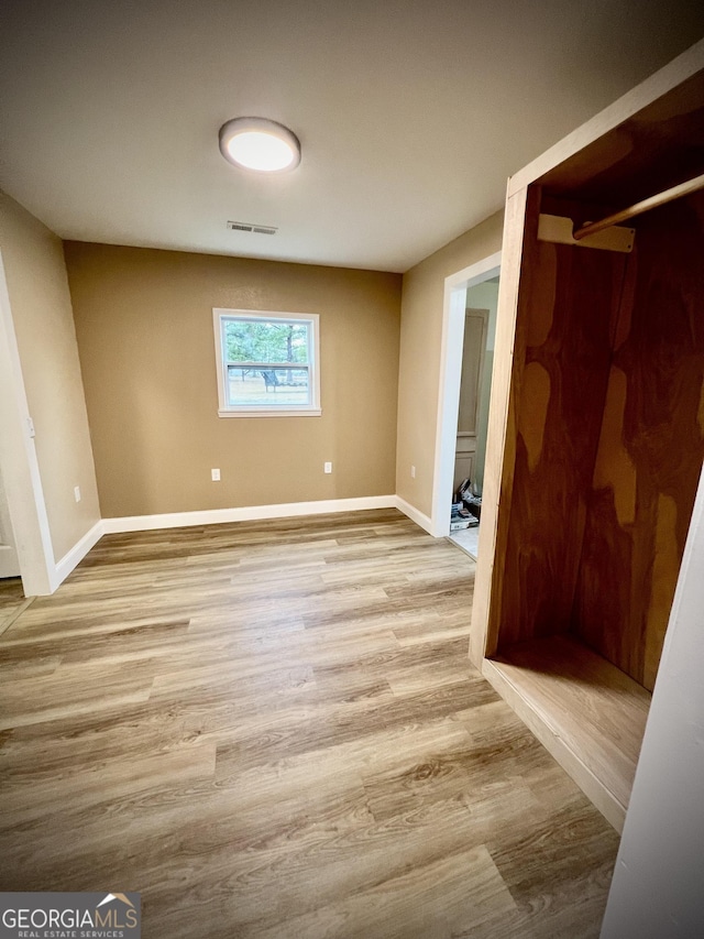 empty room featuring visible vents, baseboards, and wood finished floors