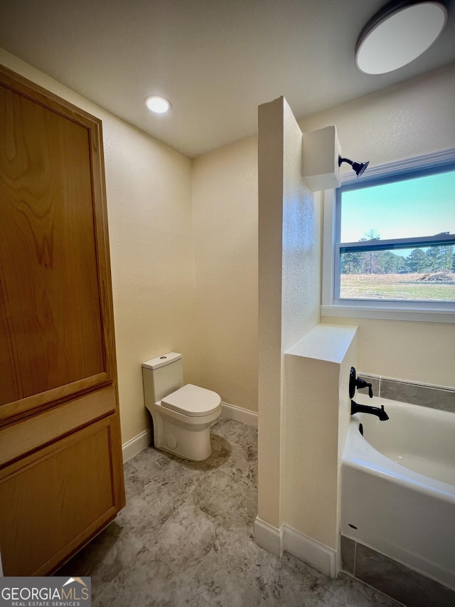 bathroom featuring a garden tub, toilet, and baseboards