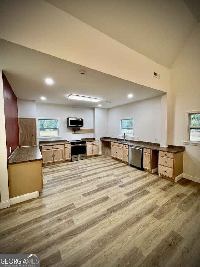 kitchen with built in desk, dark countertops, light wood-style flooring, appliances with stainless steel finishes, and a sink