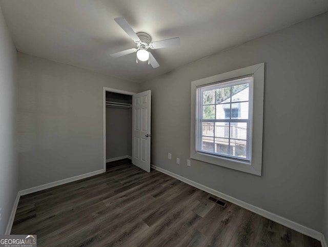 unfurnished bedroom featuring dark wood finished floors, a closet, visible vents, a ceiling fan, and baseboards