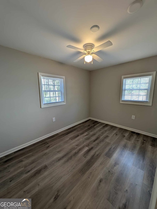 spare room with dark wood-style floors, a healthy amount of sunlight, and baseboards