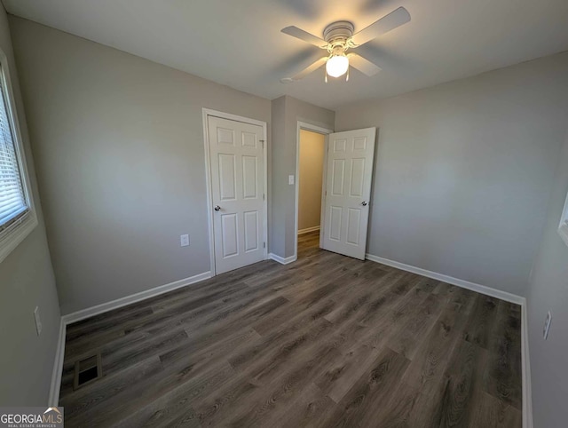 unfurnished bedroom with a ceiling fan, visible vents, baseboards, and wood finished floors