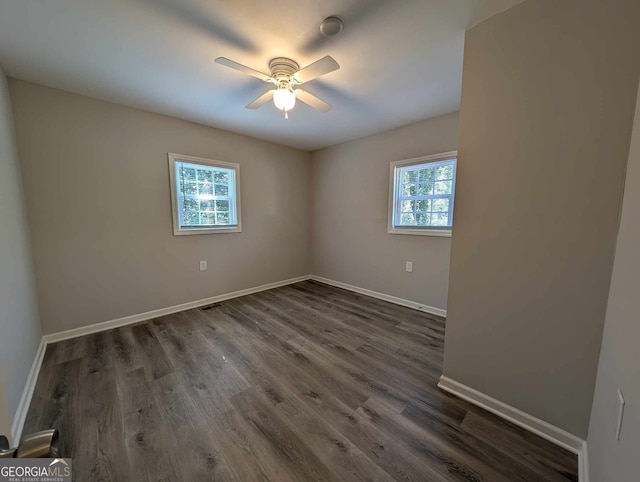 spare room with dark wood-style floors, ceiling fan, visible vents, and baseboards