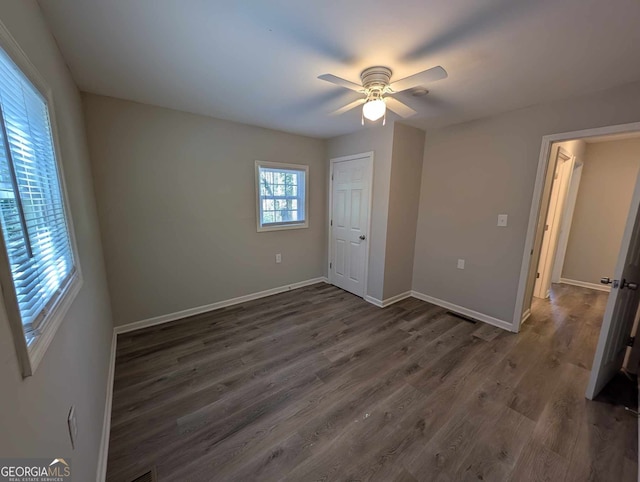 unfurnished bedroom with ceiling fan, dark wood-type flooring, a closet, and baseboards