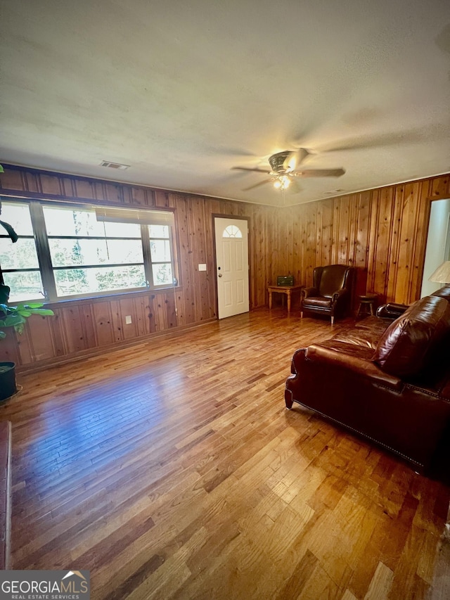 living room featuring hardwood / wood-style floors, visible vents, and a ceiling fan