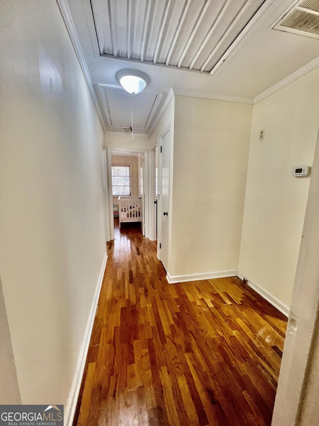 hall with attic access, visible vents, crown molding, and wood finished floors