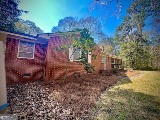 view of side of property featuring a yard, brick siding, crawl space, and a chimney