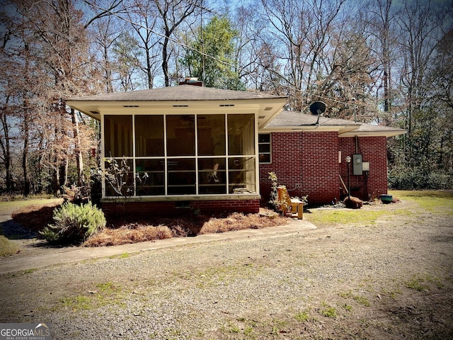 rear view of house featuring a sunroom and brick siding