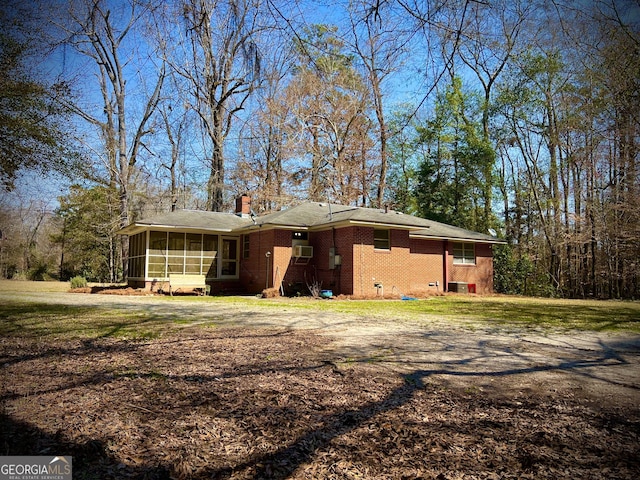 exterior space with brick siding, a chimney, a sunroom, crawl space, and a front lawn