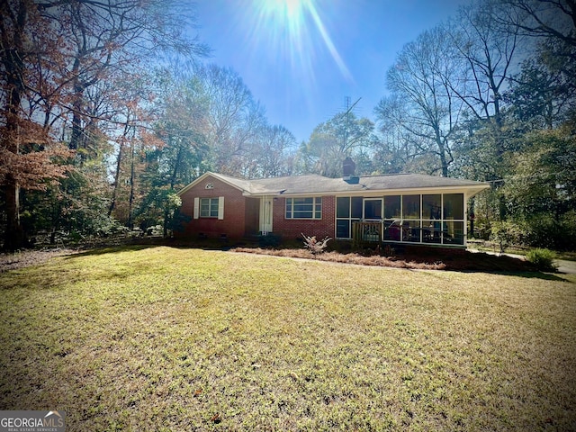 ranch-style home featuring brick siding, a sunroom, a chimney, crawl space, and a front yard