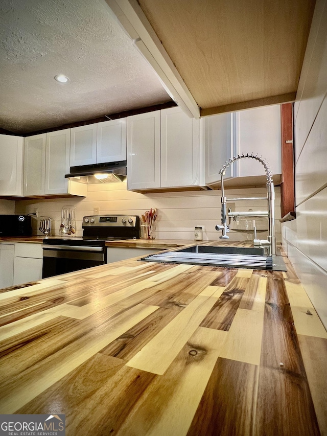 kitchen featuring under cabinet range hood, white cabinetry, wood counters, and stainless steel electric range