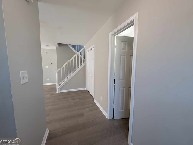 corridor featuring baseboards, stairway, and wood finished floors