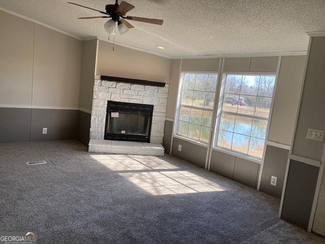 unfurnished living room featuring carpet floors, a wealth of natural light, a fireplace, and ornamental molding