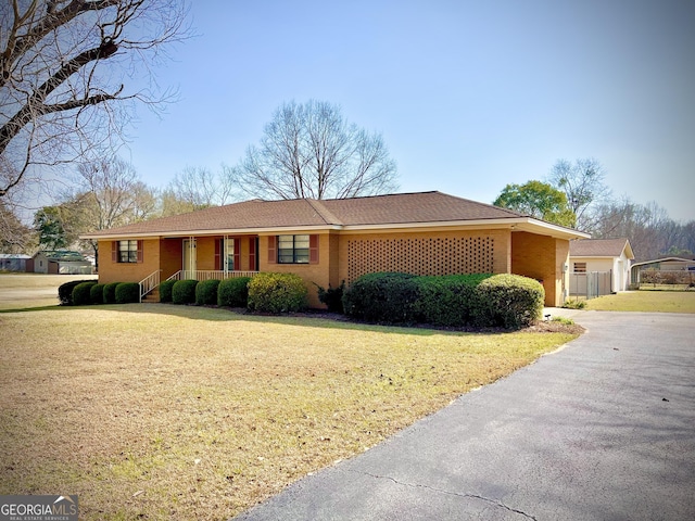 single story home featuring driveway, brick siding, and a front yard