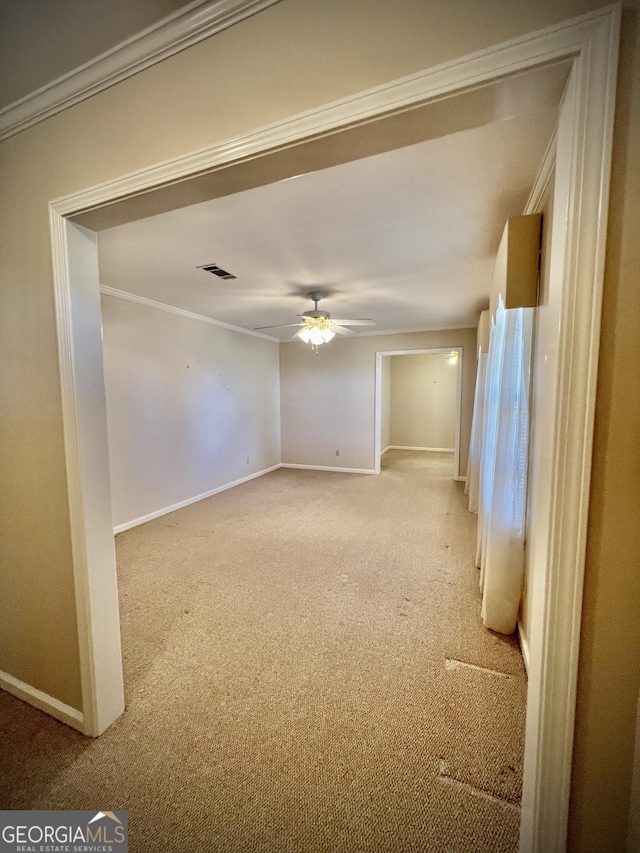 unfurnished room featuring light carpet, visible vents, baseboards, ceiling fan, and crown molding