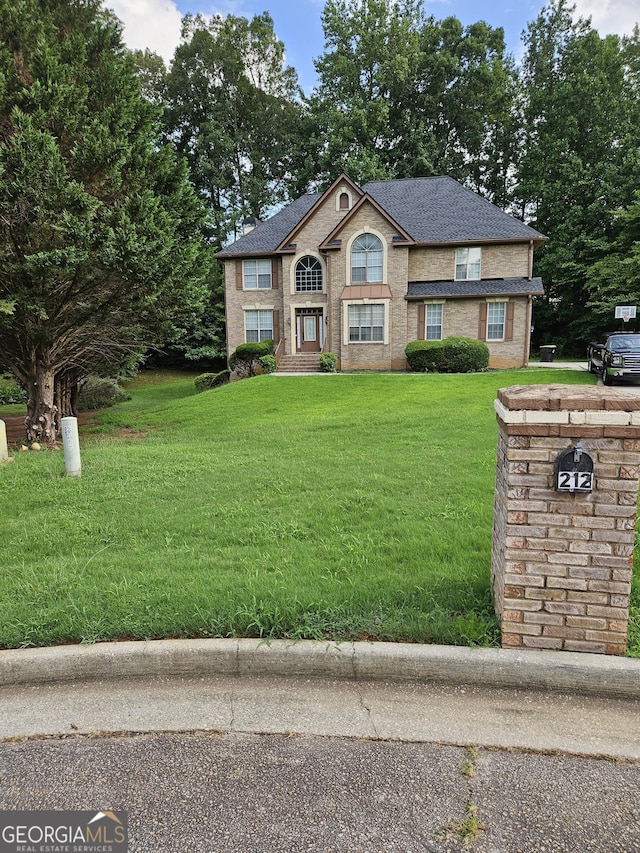 view of front of house with a front lawn, roof with shingles, and brick siding