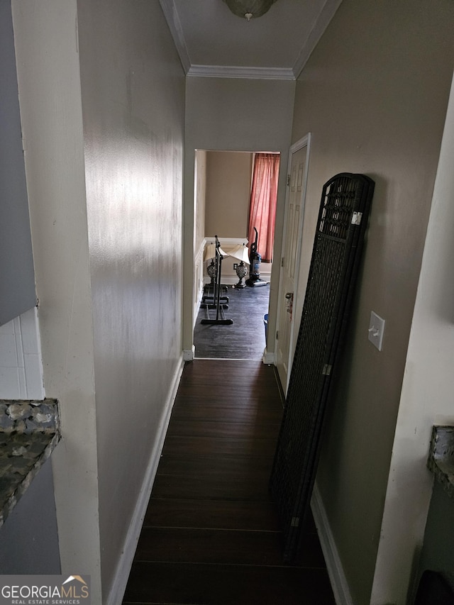 hall featuring baseboards, dark wood finished floors, and crown molding