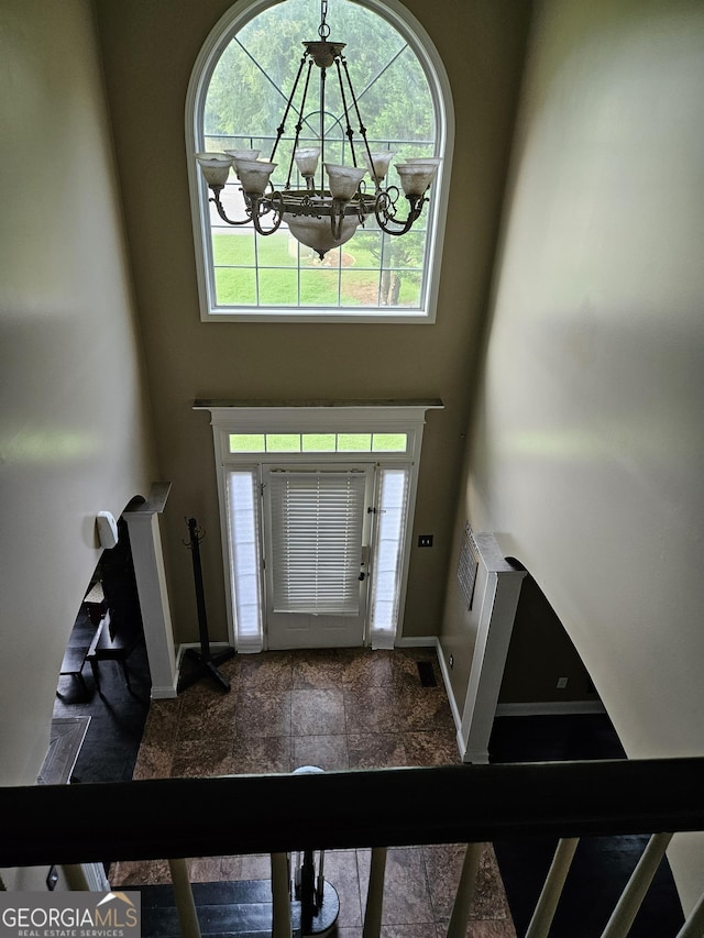 entryway with an inviting chandelier, a high ceiling, and baseboards